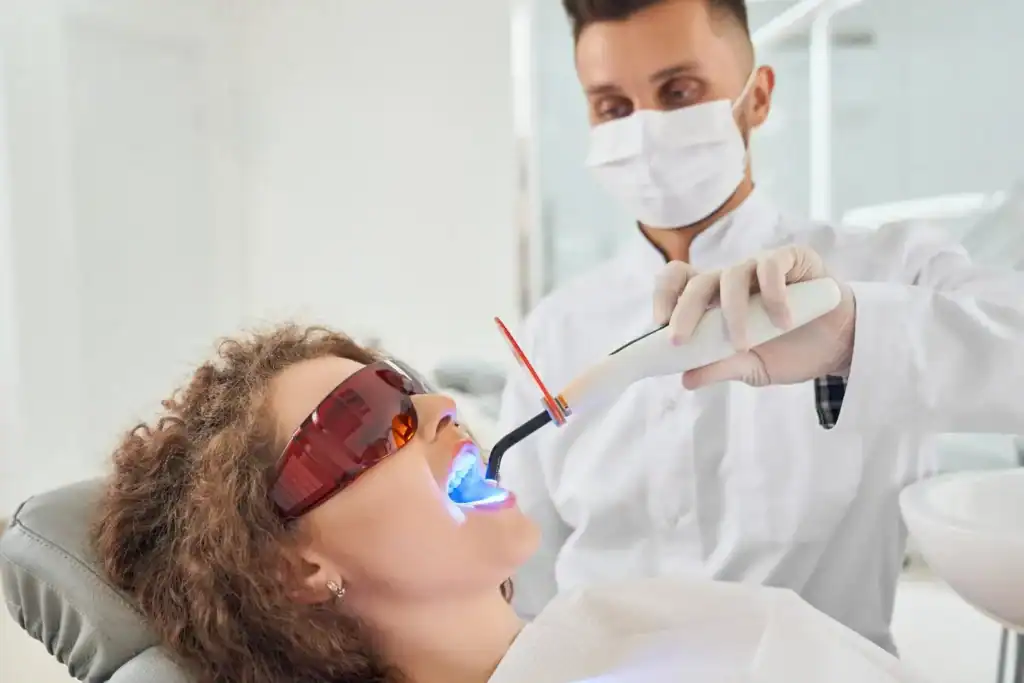 Woman receiving professional Laser Teeth Whitening treatment with safety glasses Brighton & Hove