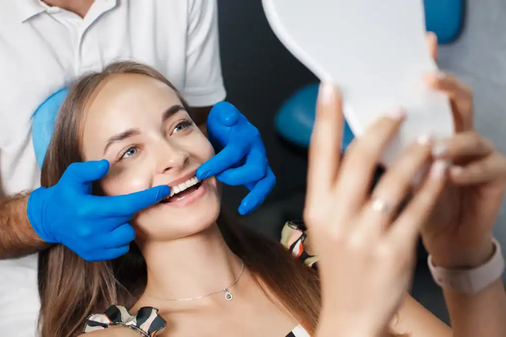 Happy patient checking results in mirror after zoom Laser Teeth Whitening treatment Brighton & Hove